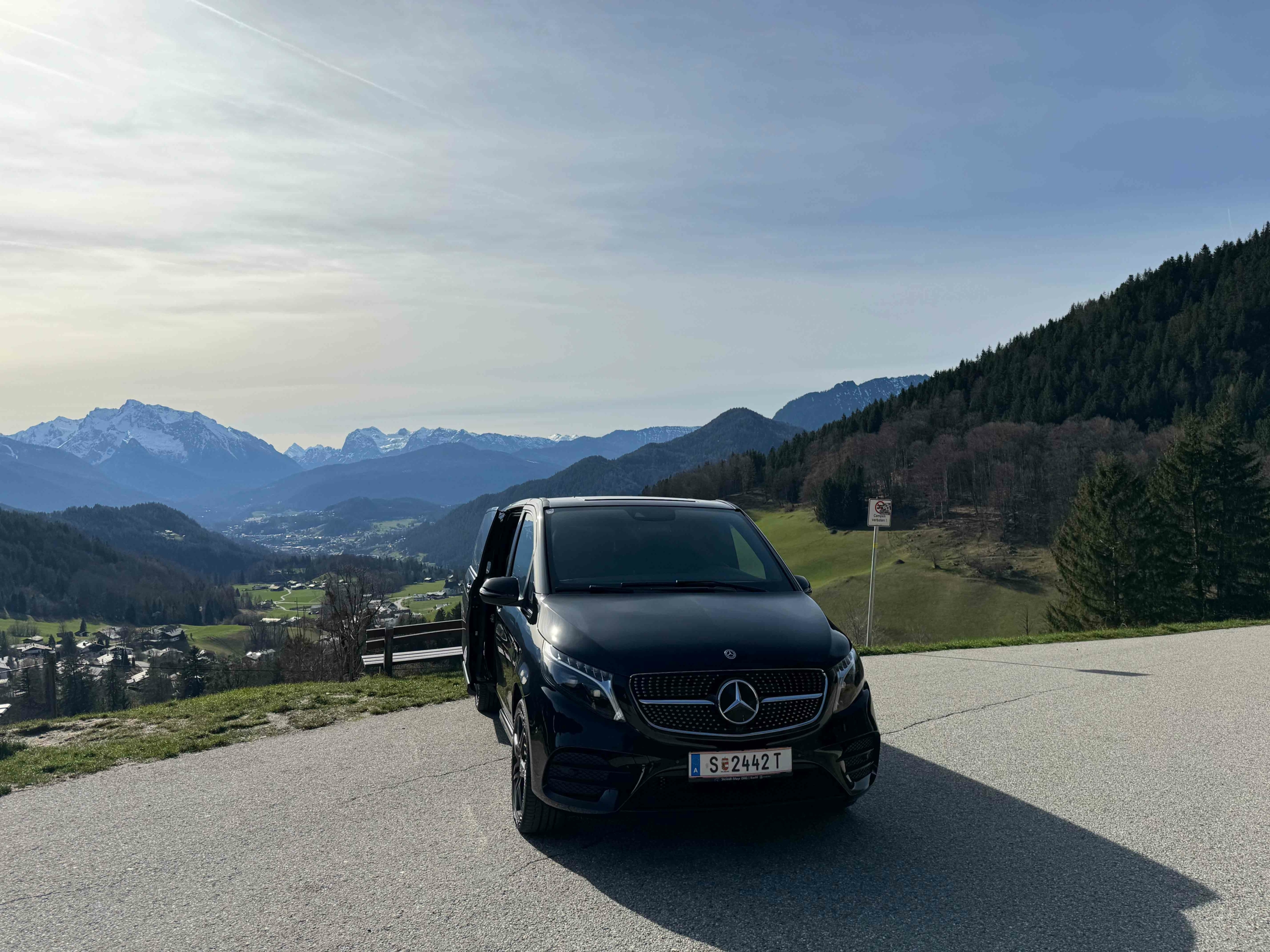 a black car parked on a road with mountains in the background